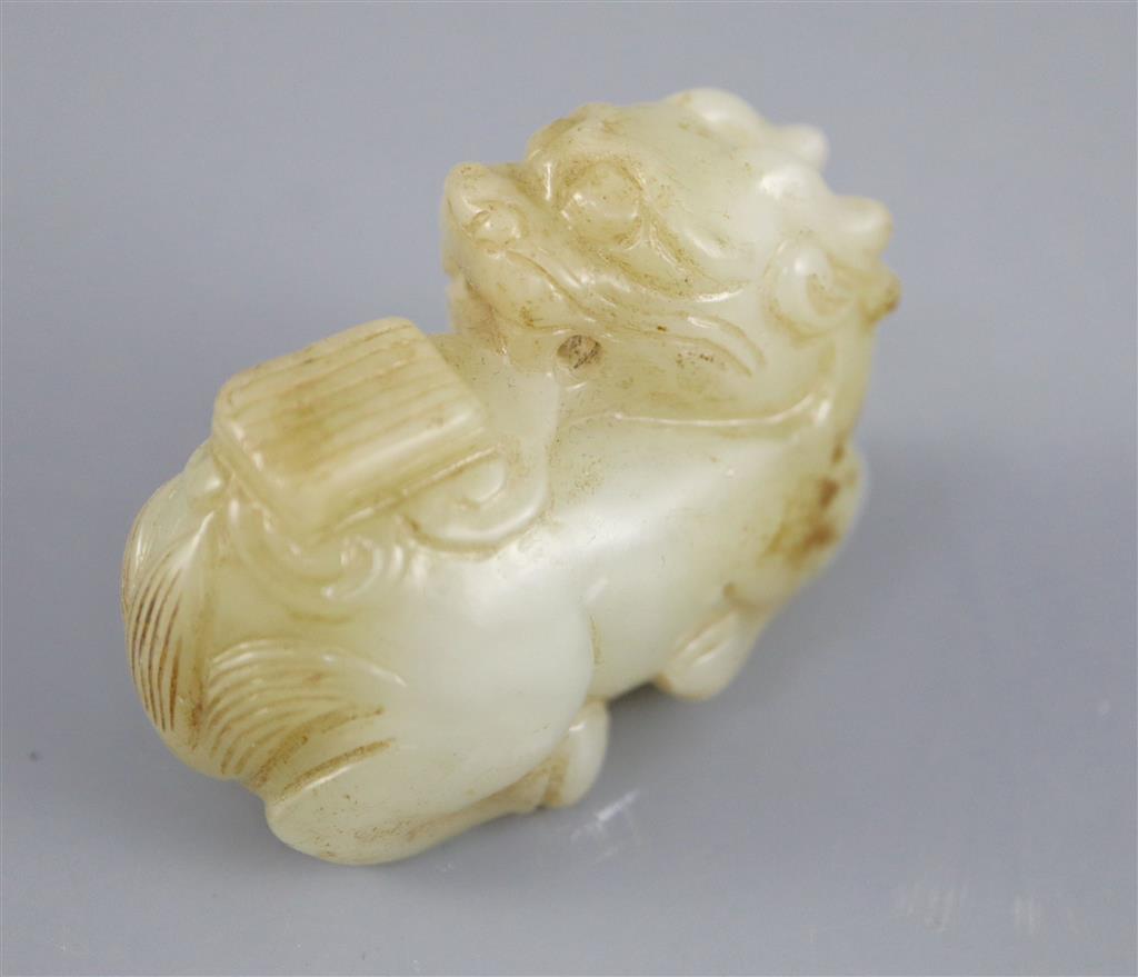 A Chinese pale celadon jade figure of a recumbent qilin, 5.4cm